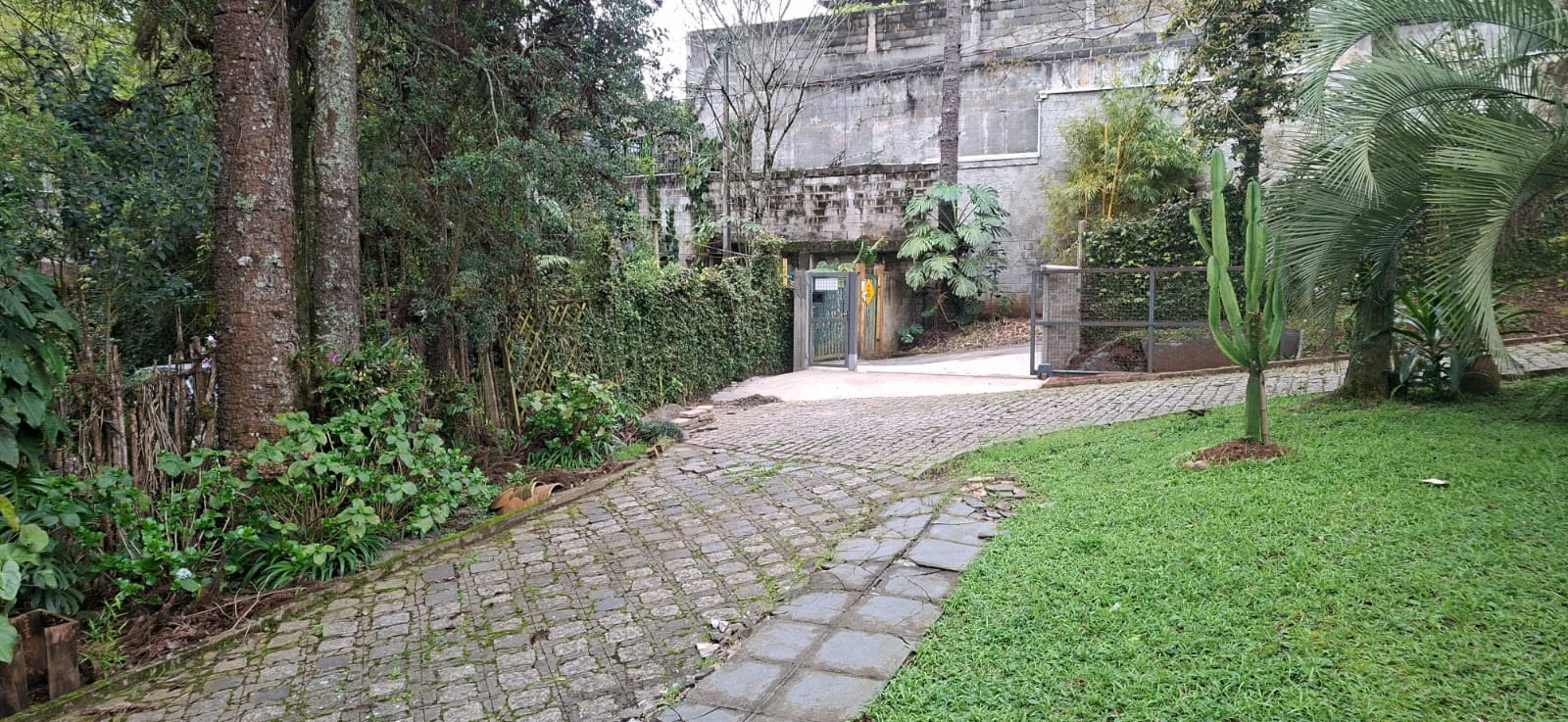 Entrada da Casa do Tecelão com portão no próprio terreno e caminho de pedras