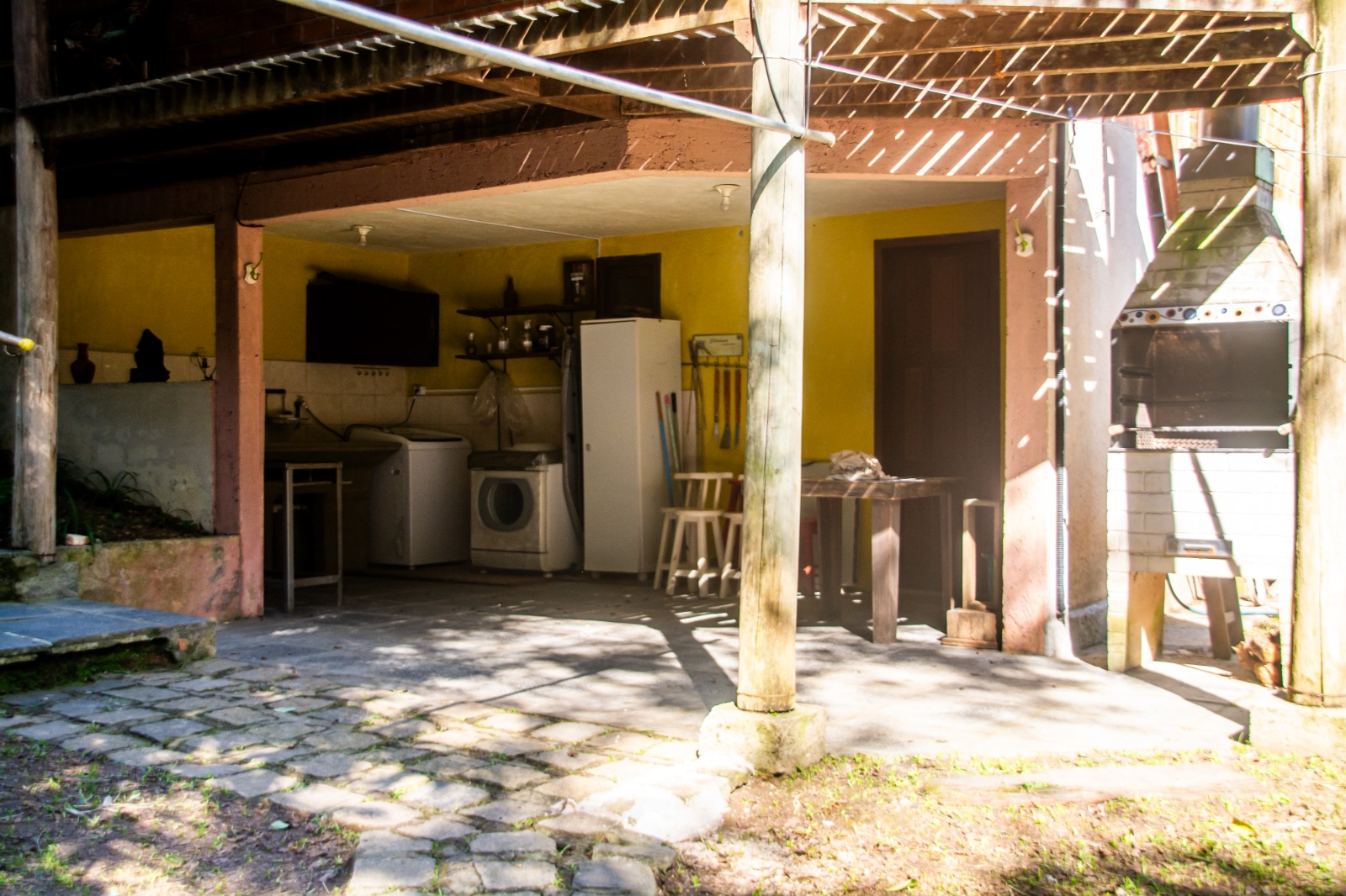 Espaço coberto com churrasqueira, lavanderia e área de apoio
