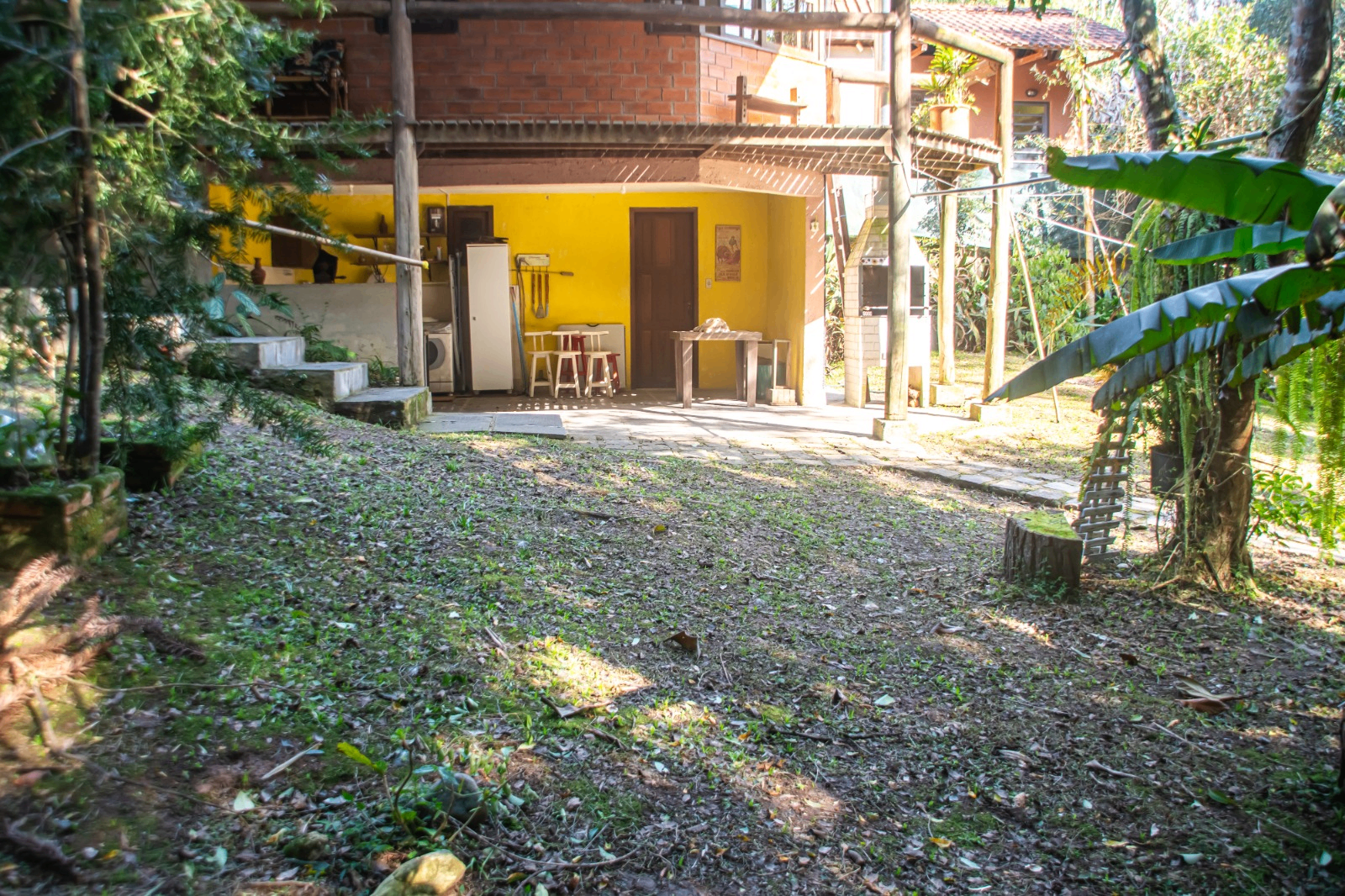 Área compartilhada vista do jardim com cozinha externa amarela