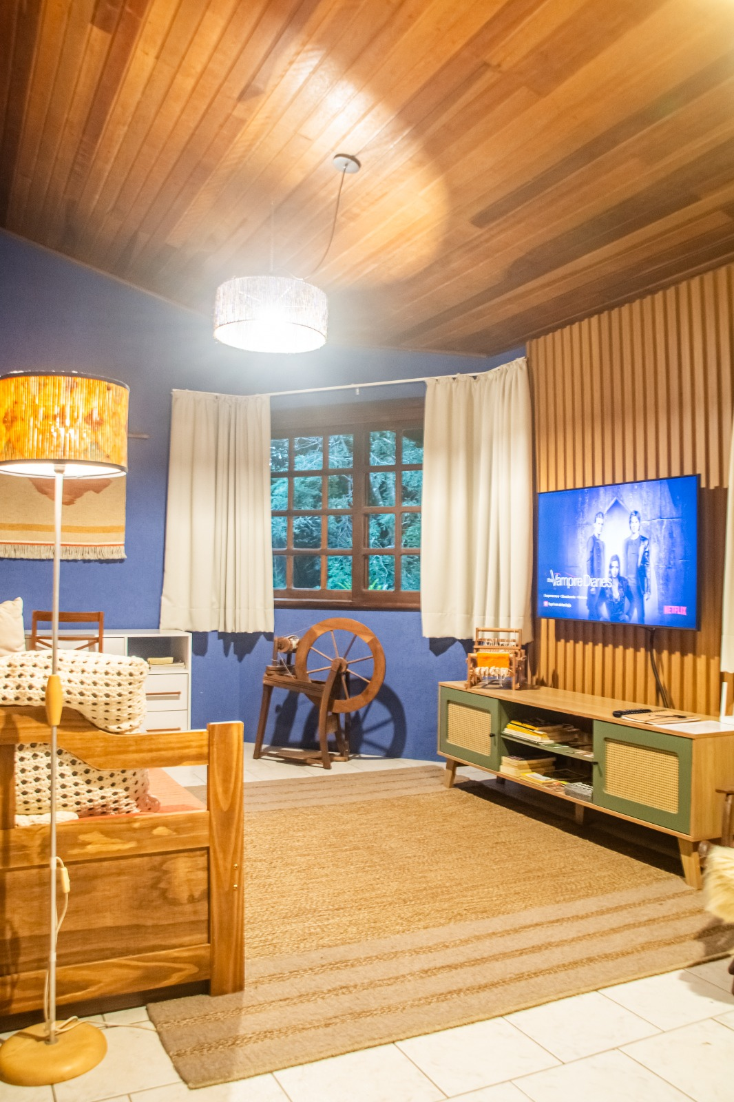 Sala interna com televisão e roda de fiar